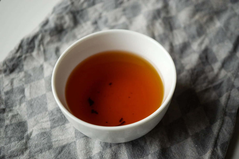 Weiße Teetasse mit schwarzem Tee