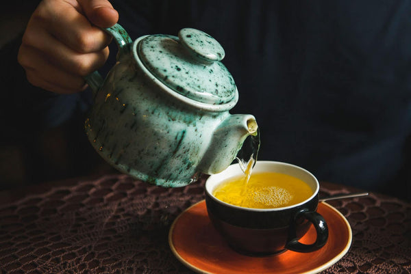 Teekanne und eine Tasse mit goldfarbenem Tee