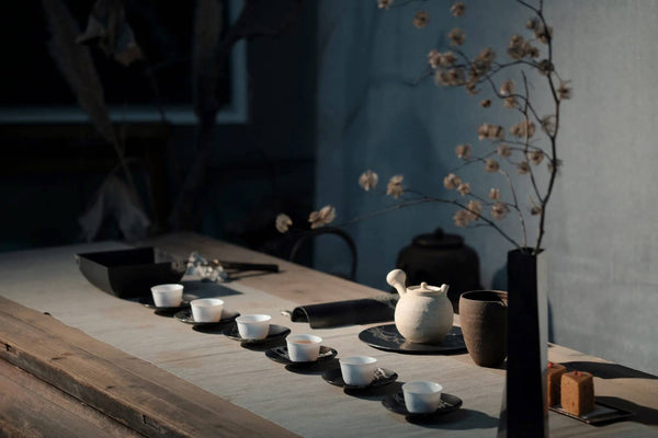 gedeckter Tisch mit einer Vielzahl von Teetassen, einer Teekanne und einer Blumenvase in entspannender Atmosphäre