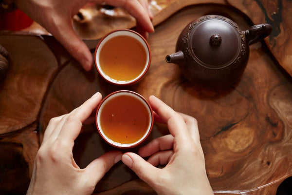 Eine braune Teekanne und zwei terracottafarbene Teetassen