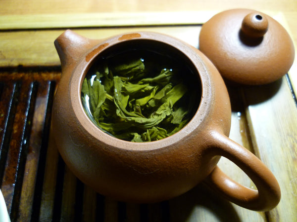 Terracottafarbene Teekanne mit ziehenden Teeblättern